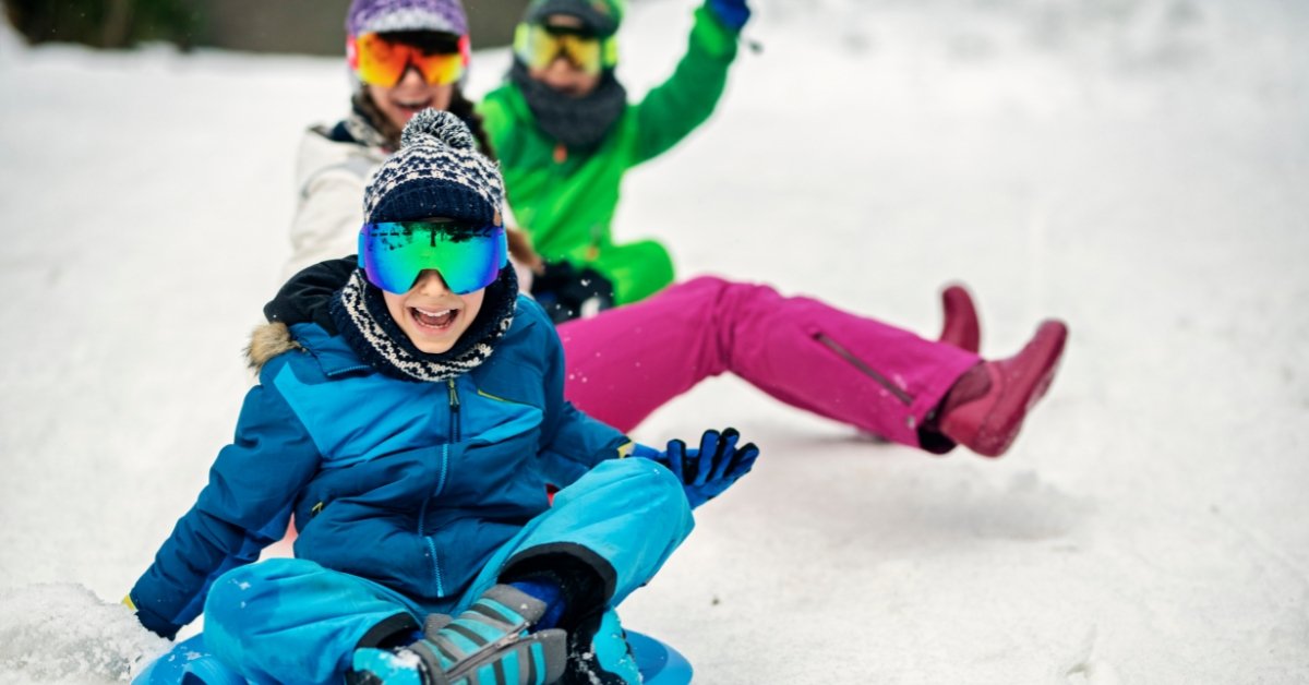 Children sledding on a Utah hillside, illustrating connection and self-preparedness through safe winter outdoor play.