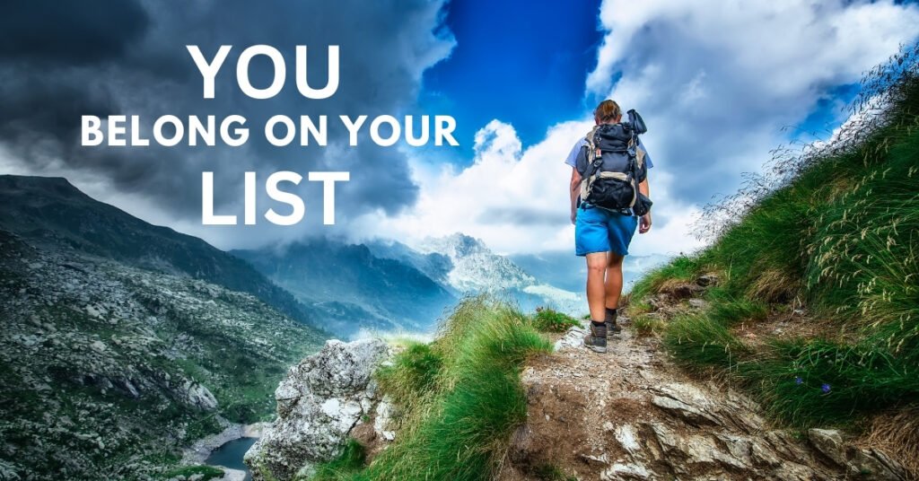 A person hiking forward on a mountain trail, with the overlaid text 'You Belong On Your List' to symbolize taking steps to self-love.