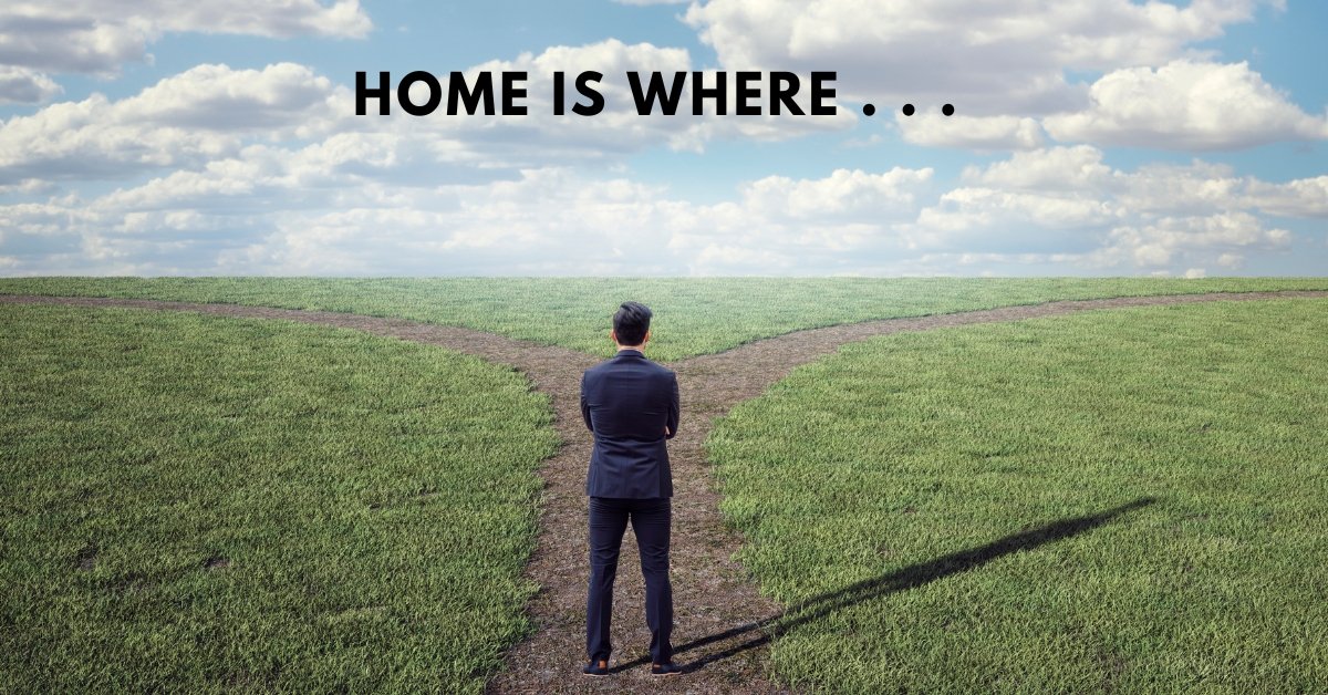 A man standing at a fork in a grassy path with the words "Home is where" above him, symbolizing the duality of belonging and the personal definition of home.